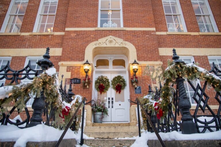 Welcome 6 Wreaths on the front white doors of a brick building at a Galena Bed and Breakfast during Christmas in Galena IL.