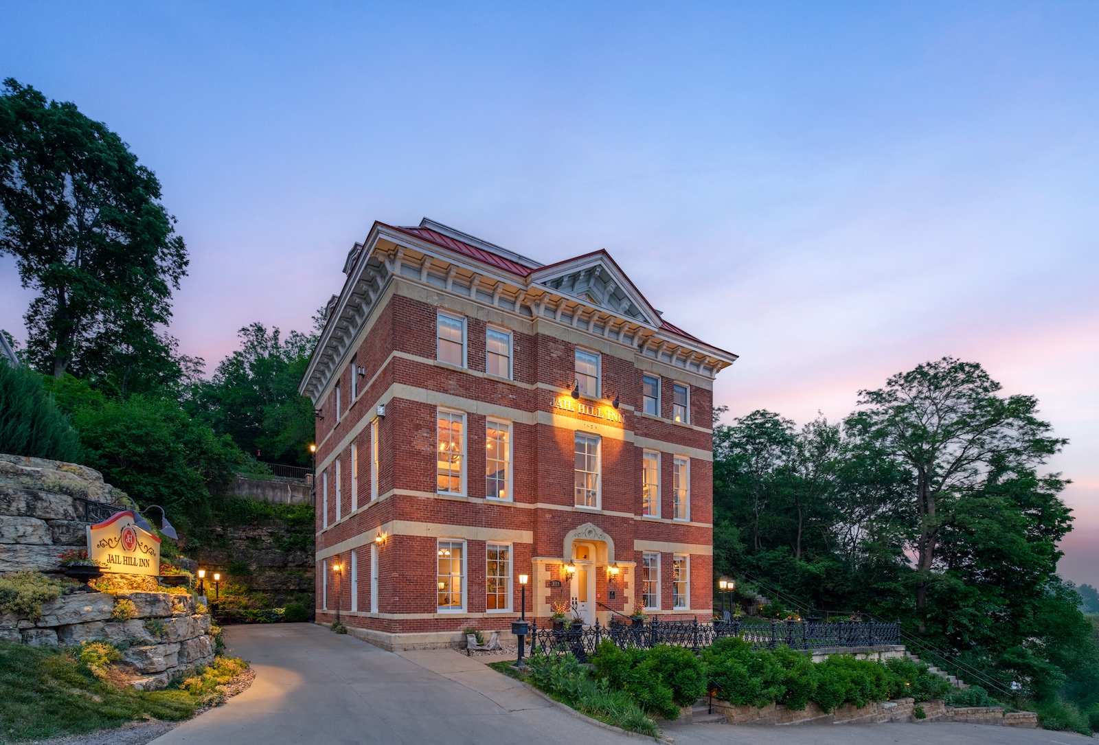 A brick building lit up at dusk that used to serve as a county jail but is now one of the best places to stay in Galena IL, especially when visiting for Galena ghost tours.