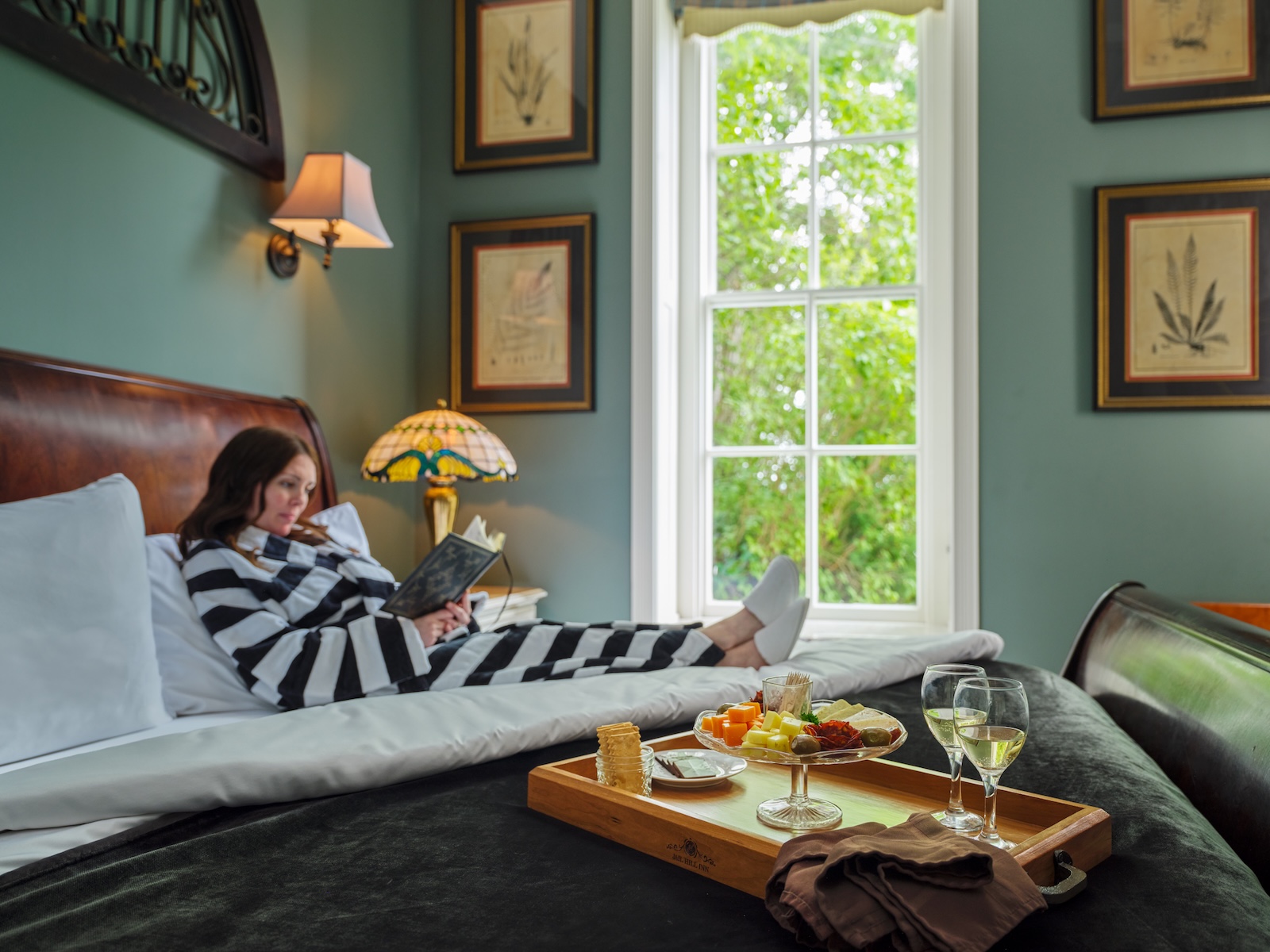A woman relaxing on a bed in a black and white striped robe at one of the best places to stay in Galena IL.