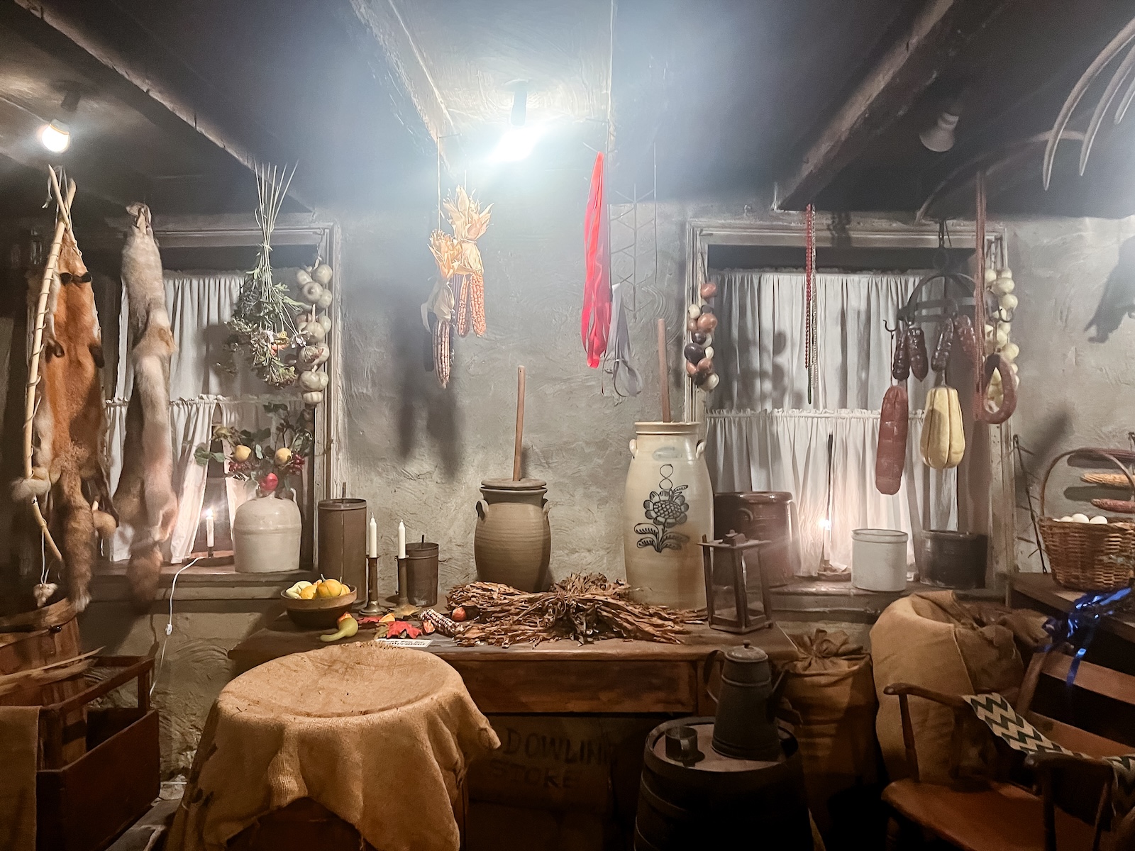 Historic interior of the Dowling House, a stop on Galena ghost tours, with period furnishings, hanging provisions, pottery, and candlelight.