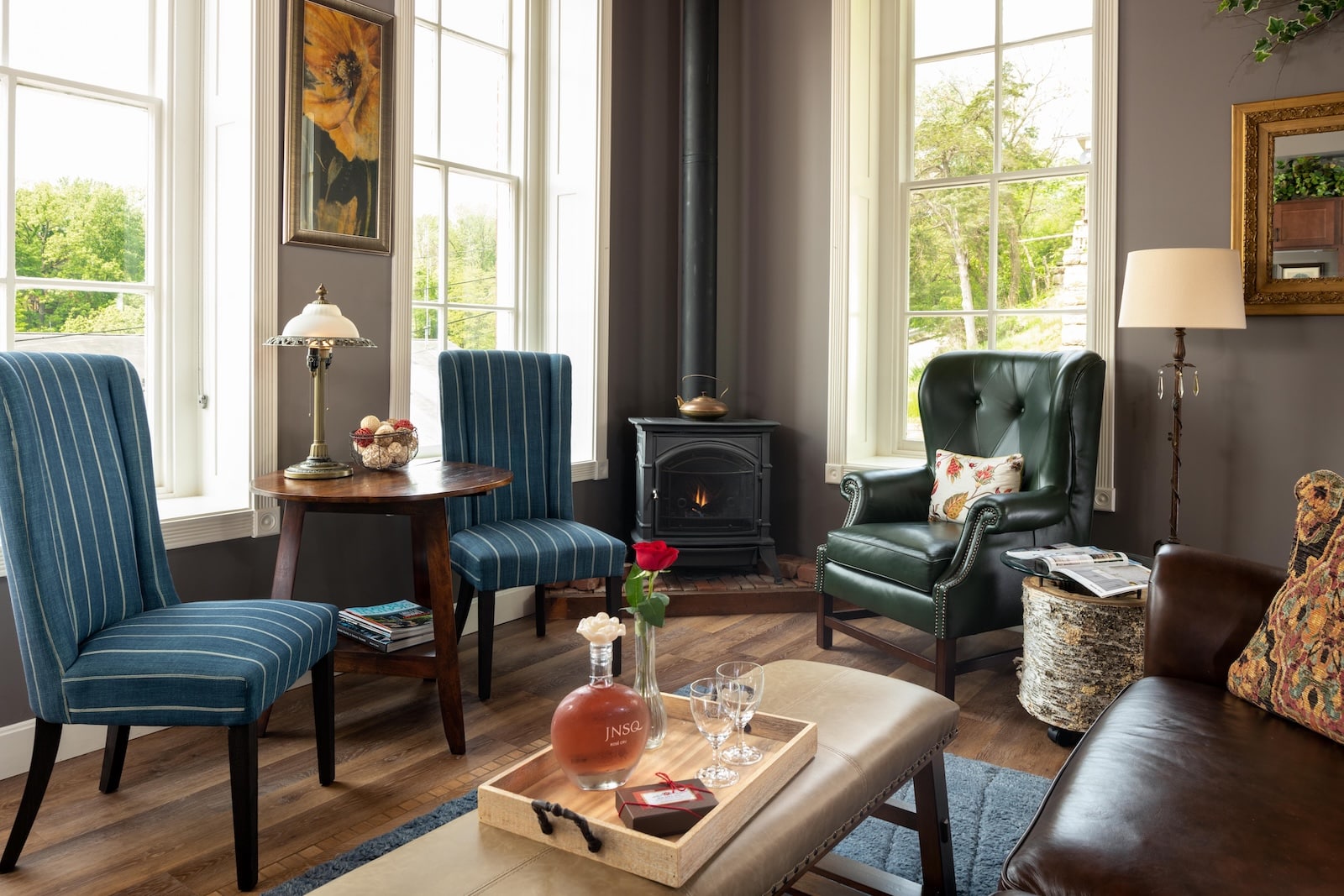 Discover the Historic Old Blacksmith Shop in Galena 2 Chairs surrounding a coffee table in a room with large windows and a fireplace, what you'll find at our Bed and Breakfast Galena IL.